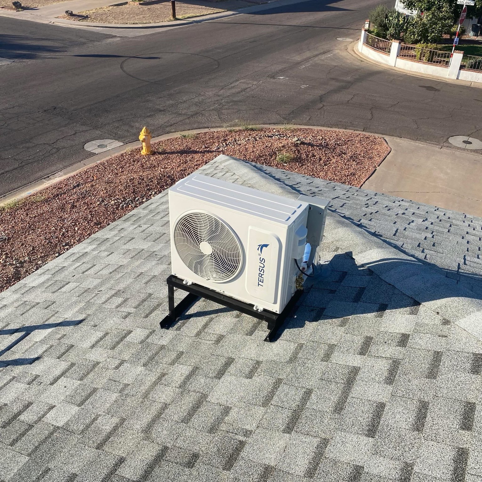 Mini split condenser positioned on rooftop supports